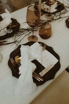 the table is set with place settings, napkins and gold utensils on it