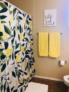 a bathroom with two yellow towels hanging on the wall and a white toilet next to it