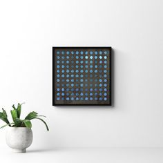 a potted plant sitting on top of a white table next to a black framed wall