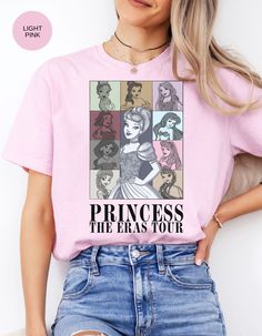 Embark on a whimsical adventure with our "Princess Eras Tour" Cotton Tee! This enchanting shirt features a delightful compilation of all your favorite Disney princesses, inviting you to relive the magic of each era. Crafted from premium cotton, it ensures comfort as you embrace the timeless charm of these beloved characters. Let your inner princess shine with this captivating and stylish tee that pays homage to the beauty of Disney's royal legacy. Join the tour and make every day feel like a fairy tale! Disney Pink T-shirt For Disney Fan Events, Disney Themed Character Print Tops, Pink Disney Top For Disney Trips, Themed Tops For Disney Trips With Character Print, Pink Cotton Tops For Disney Trips, Pink Disney T-shirt For Disney Trips, Pink Cotton T-shirt For Disney Trips, Pink Cartoon Print T-shirt For Disney Trips, Eras Tour Shirt