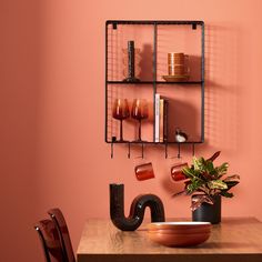 a wooden table topped with a vase filled with flowers next to a wall mounted shelf