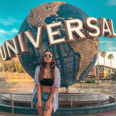 a woman standing in front of a sign that says universal with the world on it