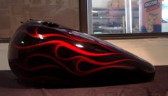 a black and red motorcycle helmet sitting in front of a store window with flames on it