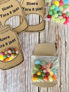 three jars filled with candy sitting on top of a wooden table next to some bags