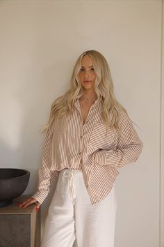 This stripe button up shirt is tailored for a boyfriend fit. The striped button down shirt features brown and white stripes with a collared neckline. Style the brown button up shirt womens with beige wide leg pants for a casual chic look. Brown And White Shirt Outfit, Beige Collared Shirt Outfit, Linen Pants Button Up Shirt, Dress And Button Up Shirt Outfit, Collared Button Up Shirt Outfit, Boyfriend Button Up Shirt Outfit, Striped Shirts For Women, Tan Button Down Shirt Outfit, Striped Linen Shirt Outfits