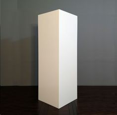 a tall white box sitting on top of a wooden floor next to a wall and wood floor