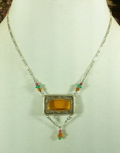 Vintage Czech Glass Choker, Amber Glass Necklace, Czech and Sterling Necklace Honey Amber Glass Necklace by Lucy Isaacs This Art Deco Lucy Isaacs antique amber Czech glass rectangular silver deposit necklace dates from the 1920s. It is framed and prong set in .925 sterling silver. It measures 1 x Cheap Vintage Glass Necklaces, Antique Handmade Rectangular Necklace, Vintage Amber Rectangular Jewelry, Vintage Amber Sterling Silver Necklace, Antique Amber Necklace With Gemstone, Antique Amber Gemstone Necklace, Vintage Amber Engraved Jewelry, Vintage Amber Jewelry With Engraved Details, Vintage Orange Gemstone Necklaces