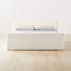 a white bed sitting on top of a hard wood floor