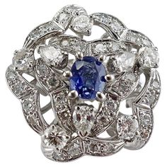 This beautiful vintage ring is finely crafted in solid 14K White gold (carefully tested and guaranteed), and set with genuine Earth mined Sapphire and diamonds. The center oval cut Sapphire measures 7mm x 5mm (1.00 carat), and this is a very clean and transparent gem of great intensity and strong brilliance. The ring holds three pear-cut diamonds (total .45 carat), five .10ct each round brilliant cut diamonds (total .50 carat), and twenty-seven single cut diamonds (total .40 carat). The diamonds Sapphire Flower Ring, Gold Band Diamond Ring, Diamond Sapphire Ring, Art Deco Sapphire Ring, Beautiful Rings Vintage, Green Tourmaline Ring, Vintage Cocktail Ring, Vintage Fine Jewelry, Gold Cocktail Ring