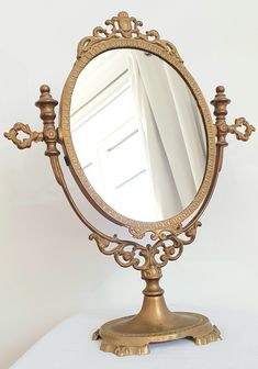 an ornately decorated gold mirror on a white tablecloth with curtains in the background