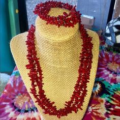 a necklace with red beads is displayed on a mannequin neck piece in front of a colorful background