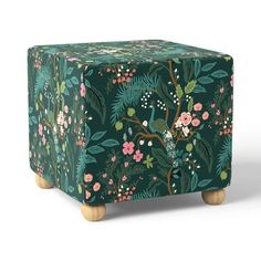 a green box with flowers and birds on the lid is sitting in front of a white background