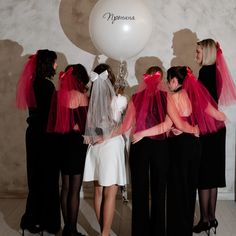 a group of women standing next to each other in front of a white ballon