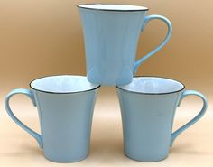 three blue coffee mugs stacked on top of each other in front of a beige background