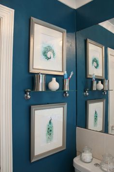 a bathroom with blue walls and pictures on the wall