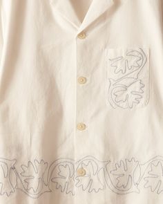 a white shirt with embroidered letters on it and two small holes in the chest pocket