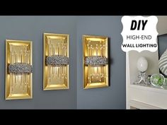 two gold wall lights are hanging on the wall next to a mirror and vases