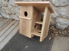 a wooden bird house sitting next to a stone wall