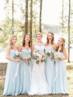 a group of women standing next to each other wearing dresses and holding bouquets in their hands