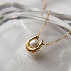 Featuring a stunning U-shaped pendant adorned with a lustrous pearl, the Ava Necklace adds a touch of elegance to any outfit. Treat yourself or a loved one to a beautiful and timeless accessory that will surely make a statement. -stainless steel, gold plated -15" with 2" extender Chic Oval Pendant Necklace For Gift, Elegant White Pearl Necklace With Initial Pendant, Classic Pearl Pendant Jewelry With Initial, Elegant Pearl Necklace With Initial Pendant And Pearl Charm, Chic Necklace With Pearl Charm As Gift, Chic Pearl White Pearl Necklace As Gift, Chic Pearl Charm Necklace For Gift, Classic Jewelry With Initial Pearl Pendant, Chic Pearl White Pearl Necklace For Gift