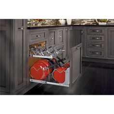 an open kitchen cabinet with two red pots and pans in the bottom drawer,