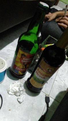 two bottles of beer sitting on top of a counter next to a bowl and knife