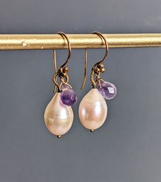 "Pich pearls accented by amethyst gemstone drops create these petite earrings. Wire wrapped securely, these plump Baroquo pearls have shimmering lustre. Dangling from 24k vermeil French ear wire, they stay on securely and are just the right length to be noticeable.  Details: Baroque Pearl (10x15mm) Amethyst Measures: just over 1.4\" ( 35mm) Dangle earrings made of 24 k gold fill and French wire. * Processing time is 3 - 5 days.  * US orders are shipped first class mail. * International orders are shipped first class international. * Shipping upgrades are available at checkout. Thank you for visiting my listing! Have a wonderful day!" Elegant Amethyst Teardrop Dangle Earrings, Elegant Dangle Teardrop Earrings With Natural Stones, Elegant Natural Stone Dangle Teardrop Earrings, Amethyst Earrings With Gemstone Accents For Wedding, Amethyst Gemstone Earrings For Wedding, Amethyst Gemstone Wedding Earrings, Wedding Earrings With Amethyst And Gemstone Accents, Wedding Amethyst Earrings With Gemstone Accents, Teardrop Amethyst Earrings For Wedding