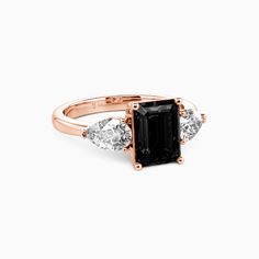 an emerald and diamond ring with three diamonds on the band, set in rose gold