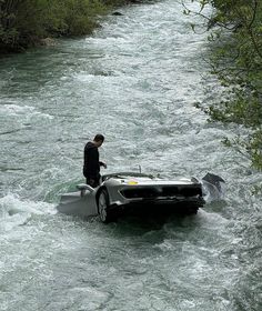 a man standing on top of a boat in the middle of a river next to trees