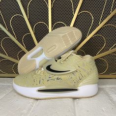 a pair of yellow nike shoes sitting on top of a white tile floor next to a golden screen