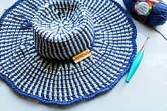 a blue and white hat sitting on top of a table next to crochet hooks