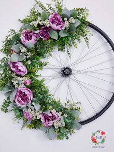 a bicycle wheel with flowers and greenery on it