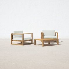 two chairs and a coffee table in front of a white wall with no one sitting on it