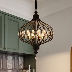 a chandelier hanging from the ceiling in a kitchen with green cabinets and cupboards