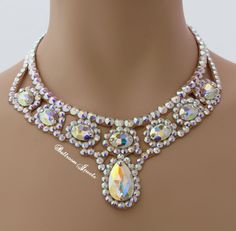 This necklace was created with Crystallized™ Swarovski Elements aurora borealis clear crystals. The necklace is 2 ¾ inches at the widest point in front and tapers in the back for comfort. There is a large pear shaped stone in the front and oval stones wrapping up the sides creating this dramatic look! This will fill in the neckline of your dress! The stones are not secured with any metal fittings so this will not snag your costume or your partners. This design will match any dress that you own b Elegant Teardrop Necklace With Large Stone, Oval Jeweled Crystal Jewelry, Oval Crystal Necklaces For Parties, Silver Oval Bridal Necklace, Oval Stone Necklaces For Wedding, Elegant Party Jewelry With Large Stone, Teardrop Crystal Necklace With Stones, Teardrop Crystal Necklaces With Stones, Jeweled Teardrop Necklace For Wedding