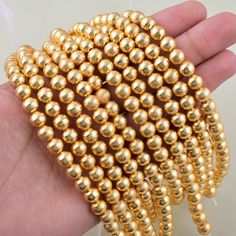 a hand is holding some gold colored beads