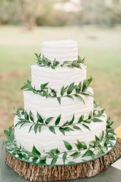 four different wedding cakes with greenery on each tier and white frosted cake in the middle