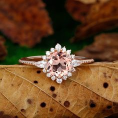 a pink diamond ring sitting on top of a leaf