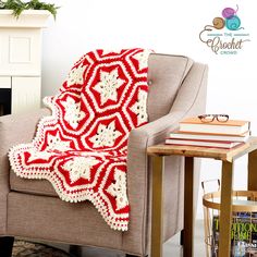 a red and white crocheted afghan sitting on top of a chair next to a fire place