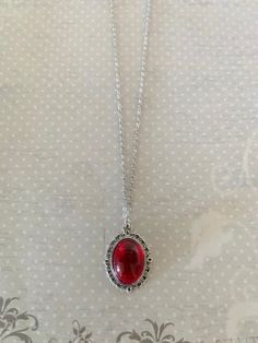 "This pretty oval shaped necklace in tibetan silver and red has an intricately designed edging with a red crystal center stone.   Pendant measures 1 1/8\" L X 3/4\" W and is on an 18\" chain.    ★ Want to see more?  Please visit my shop at: https://www.etsy.com/shop/DesignsByPeg" Cheap Red Spiritual Necklaces, Red Stone Pendant, Red Stone Jewelry, Red Stone Necklace, Red Crystal Necklace, Red Necklace, Red Gifts, Necklace Red, Cute Necklace