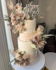 a three tiered wedding cake with flowers on top