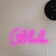 a neon sign that reads, oh la la on the wall next to a clock