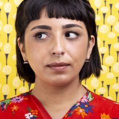 a close up of a person wearing a red shirt with flowers on it and a yellow background