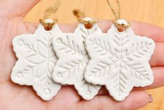 three snowflake ornaments are being held in someone's hand