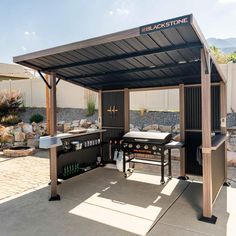 an outdoor bbq with grills and tables under a covered area in the back yard