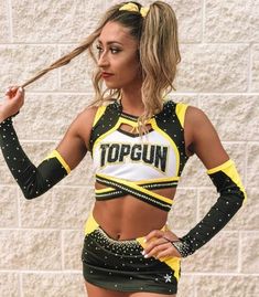 a woman in a yellow and black cheerleader outfit posing for the camera with her hand on her hip