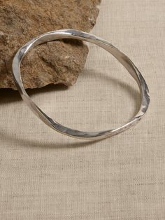 a thin silver bracelet sitting on top of a rock