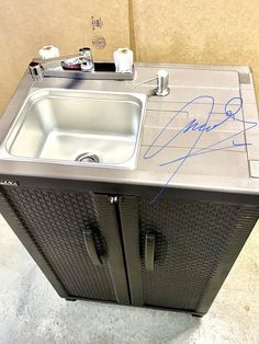 a kitchen sink with autographs on the top and side panels, in front of a wall