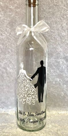 a glass bottle with a silhouette of a bride and groom holding hands on the label