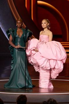 two women on stage one in a pink dress and the other in a green gown